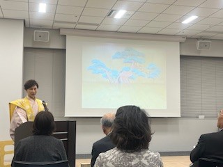JF本部の一室にて、スクリーンの前で来場席に向かって話す三宅藤九郎氏。