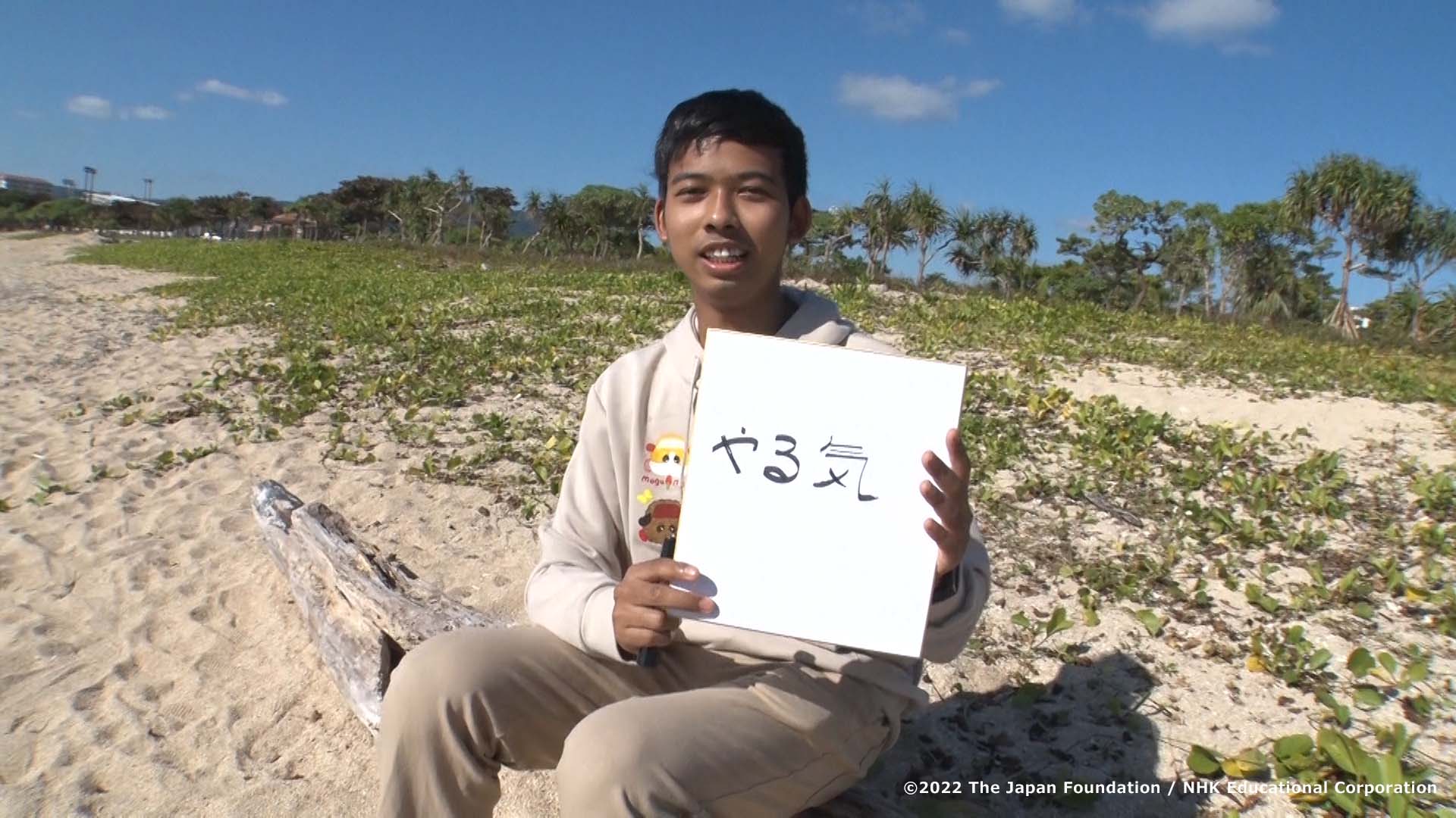 Picture of a scene showing a man holding a card that says やる気 (motivation) 