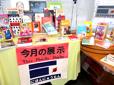 Books displayed on a table with a yellow tablecloth and a piece of paper with the title of this month's exhibition, Nihon Nyumon, written on it.