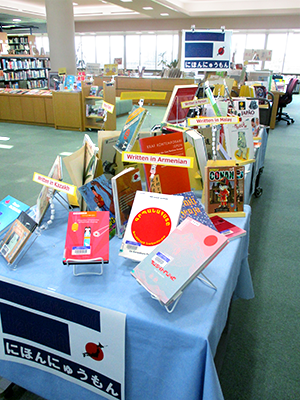 Books on display lined up on a table covered with a blue tablecloth