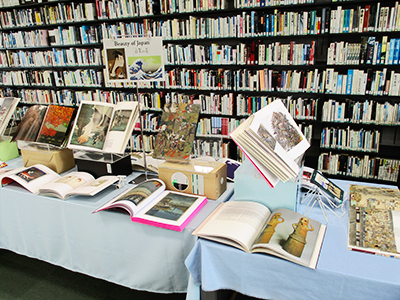 Books displayed on a table with a yellow tablecloth and a piece of paper with the title of this month's exhibition, Nihon Nyumon written on it.