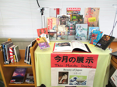 Books on display lined up on a table covered with a blue tablecloth