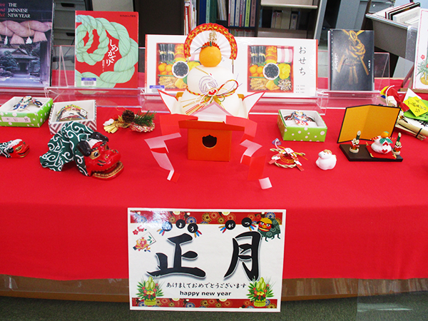 関西国際センターの図書館の入り口を入ってすぐのテーブルに、鏡餅や門松、小さな獅子舞などのお正月飾りが飾られている。