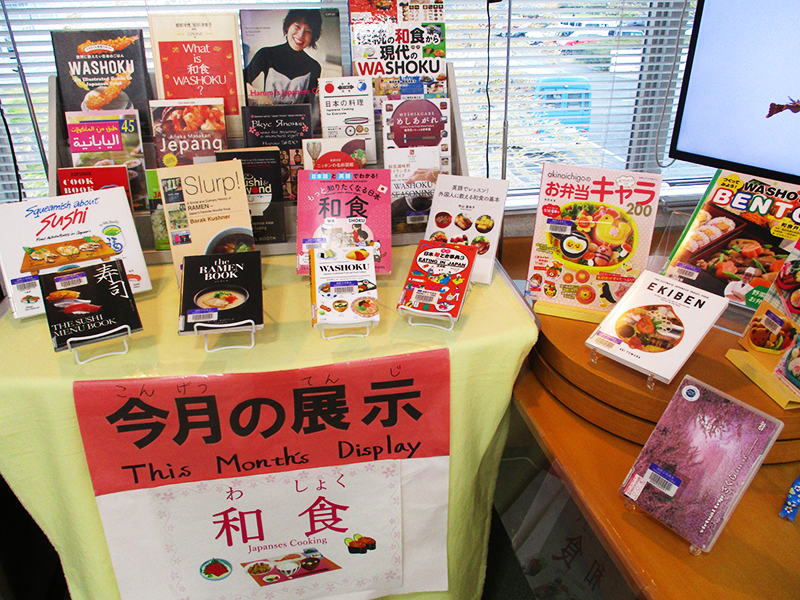4月の展示テーマである「和食」と書いてある紙がある台の上と、その横の台に、和食や弁当に関する図書が約30冊並んでいる。