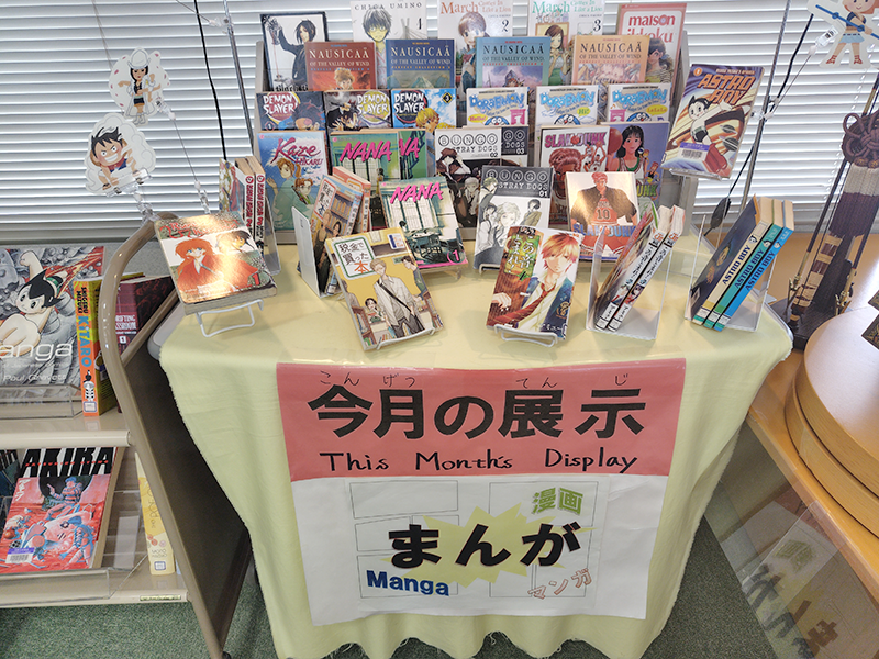 テーブルの上に5月の展示テーマである「マンガ」が多数ディスプレイされている。