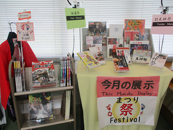 小さなテーブルに7月の展示テーマである「祭」関する本が13冊が並んでいる。テーブルの横にある小さなラックにも、さまざまな祭り関する本が並んでいる。