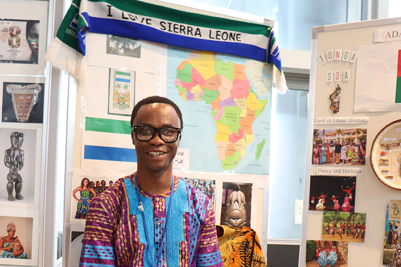 A man is standing in front of the Sierra Leone booth.