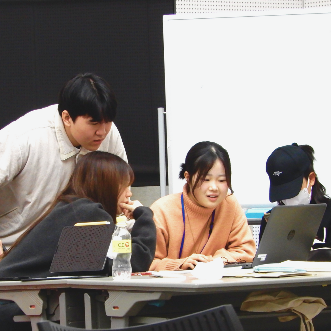 パソコンの画面を見ながら男女4人が会話をしている