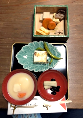 寿の箸袋に入った割り箸を手間に置いて、お雑煮、黒豆、卵焼き、高野豆腐などのお節料理