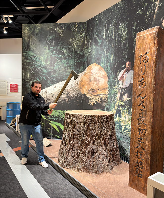 入植地の展示で木こり用の斧を持っているヴィニシュス・ボルゲス・デ・アルメイダ氏。