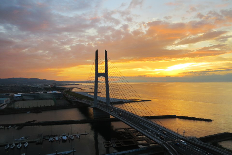 泉南市のイオンモールの道中で、夕焼けと海と橋の景色が広がっている。
