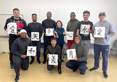 毛筆で書かれた一文字を手にして10人の集合写真