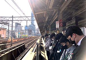 JR大久保駅のホームで線路に向かって横一列に並んで黙とうをささげる人達
