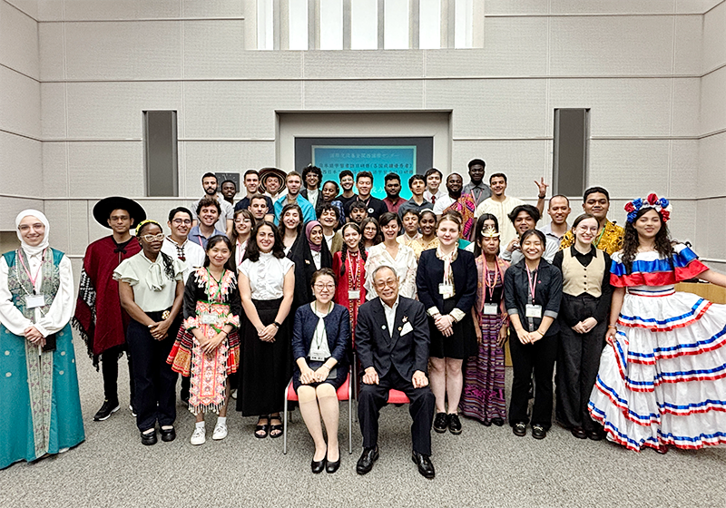 会場に参加者が集まって記念撮影 中には民族衣装で参加している人も数人見られる
