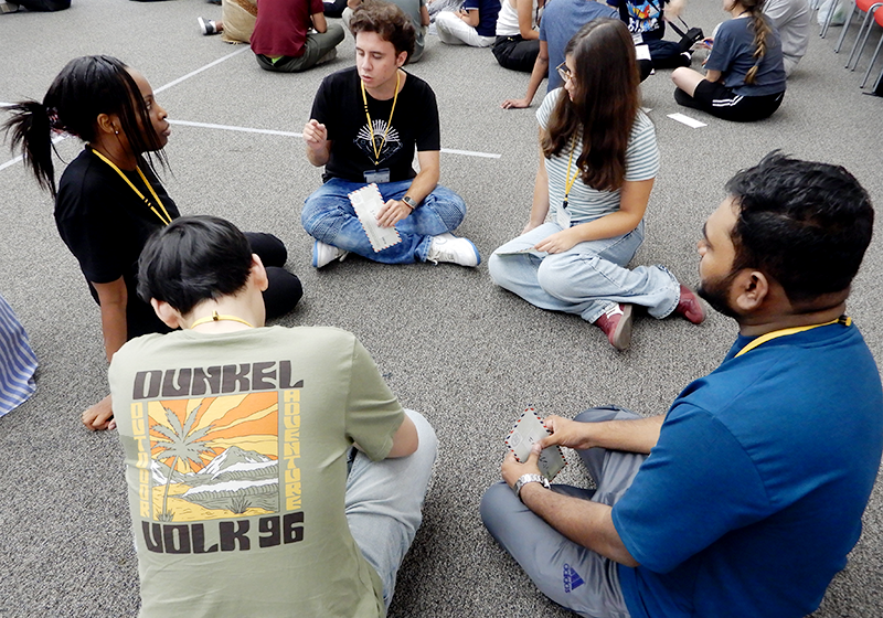 床に5人の男女が車座になって座っている