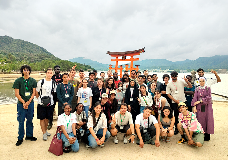 海の中の鳥居を背景に参加者4～50名で記念撮影をしている
