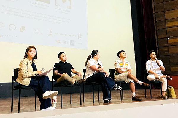舞台上に5人の登壇者が椅子座っており、右端の男性がマイクをもち話している