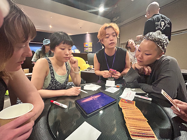 A group of about four people discussing something around a table in a studio-like space