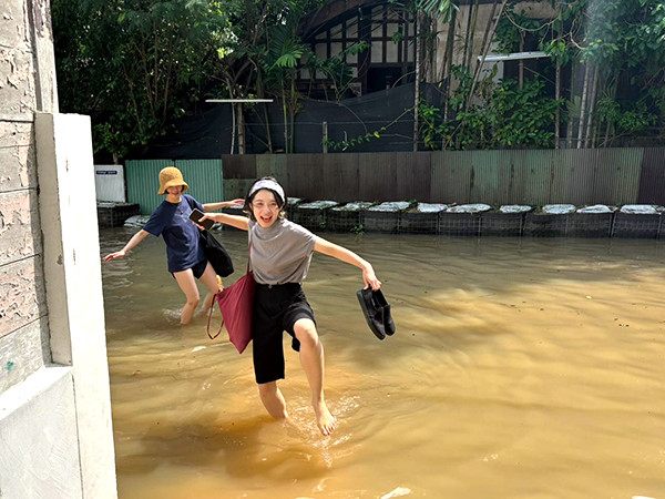 Two women walking hand in hand through a flooded street