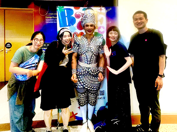 A man dressed in Thai traditional clothing is flanked by a man and woman and two women on either side.