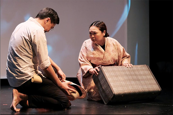 舞台上二人の演者が膝をついている