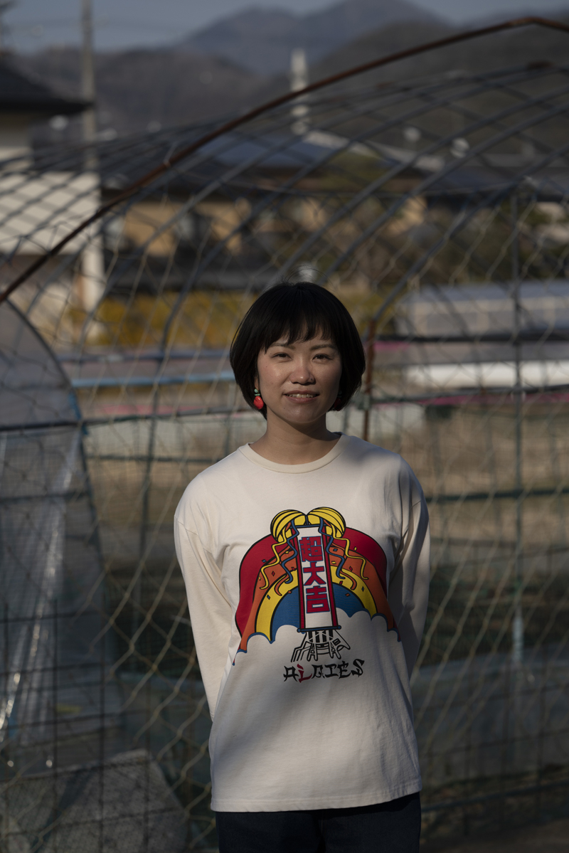 Nagara Wada is standing in front of the vinyl greenhouse.