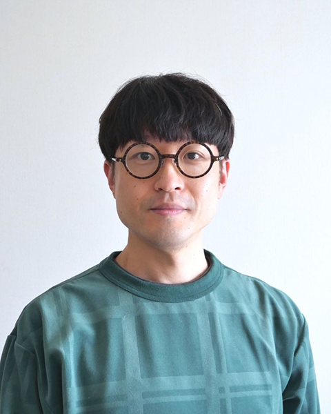 ターコイズブルーのセーターを着ている細川洋平のポートレート。