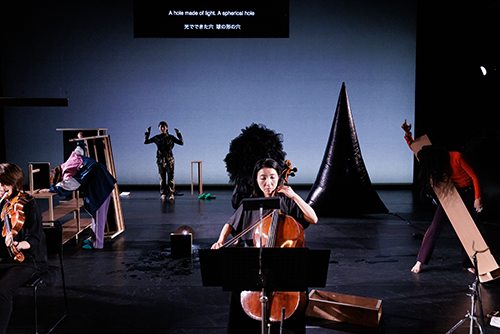A performance is being performed from the front, with a string instrument player visible in the center front.