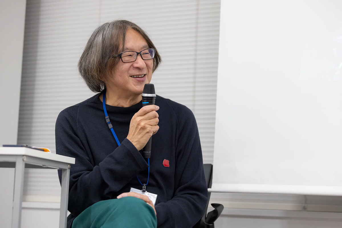 報告会の様子：マイクを持ちにこやかに発言する杉田敦氏