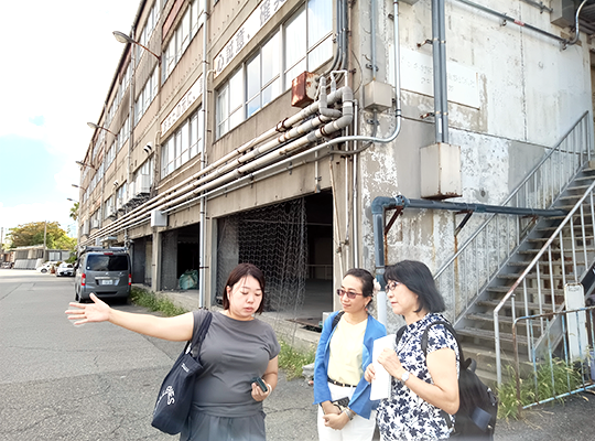 1. Three women having a conversation in front of a three-story concrete building