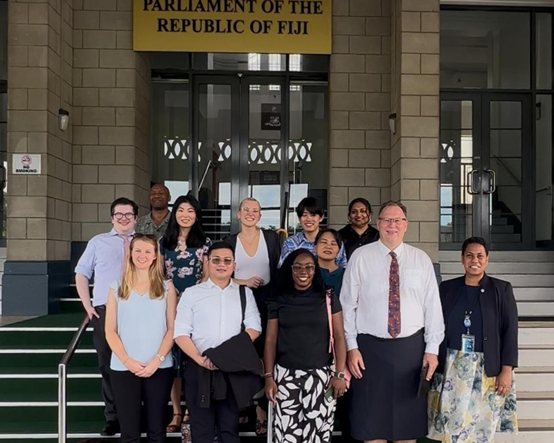 フィジー共和国議会の前で12名が記念撮影をしている。