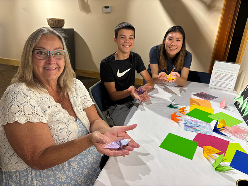 完成した鶴を掌に載せ笑顔の写真