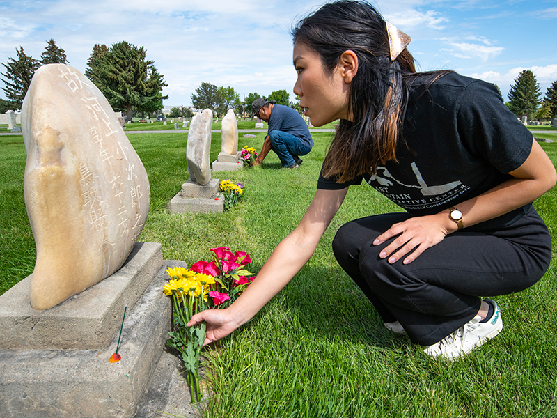 女性が墓石に花をお供えしている