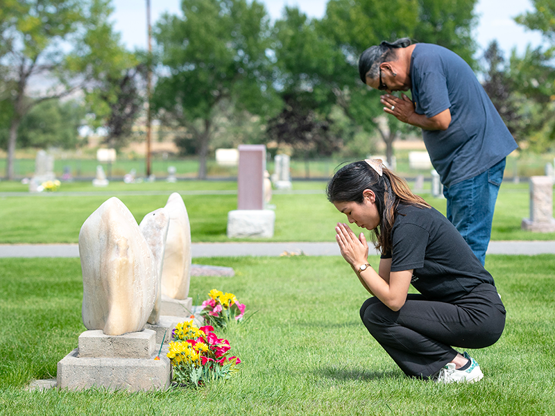 墓石の前で手を合わせる女性