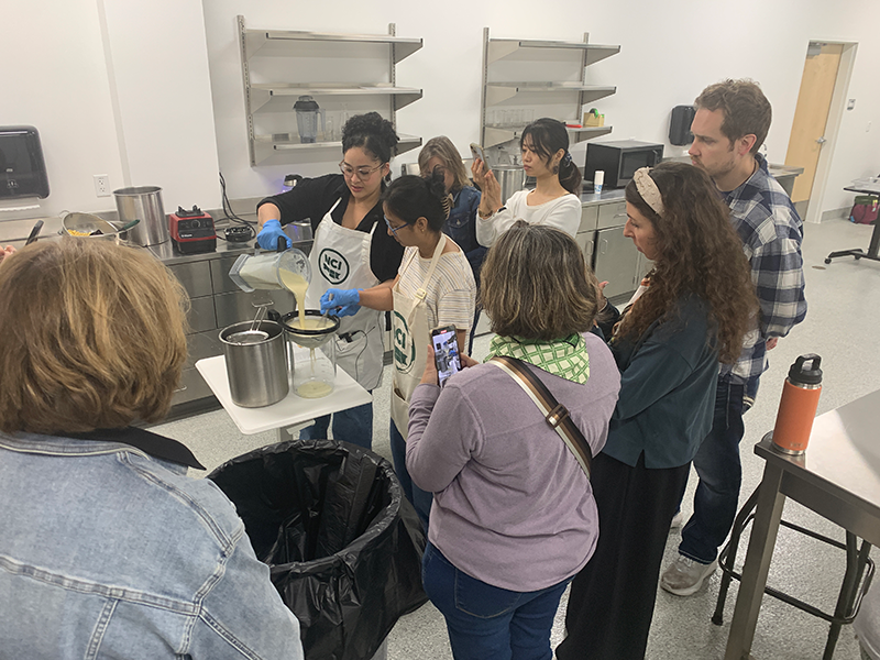 現地の人から豆腐作りを教えてもらっている様子