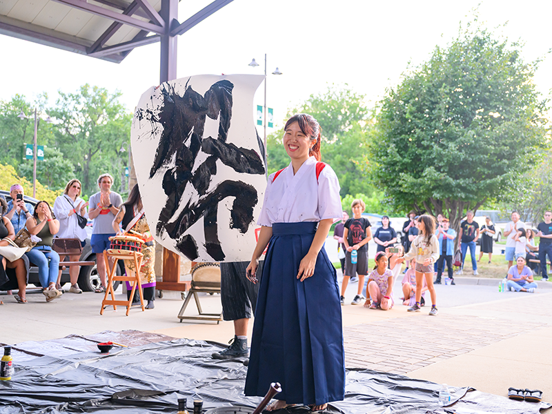 大きな半紙に書道で「祭」の文字を書き終わり笑顔の参加者
