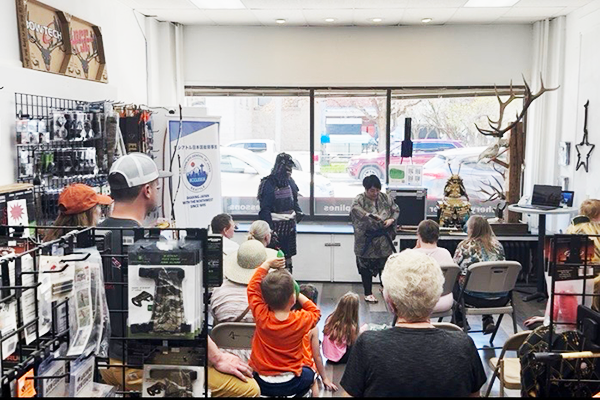 モンタナ州ディロンの日本祭りを開催しているアーチェリーショップの一角にて、観客10名以上がいる中で、日本人1名が鎧・侍のプレゼンテーションをしている。