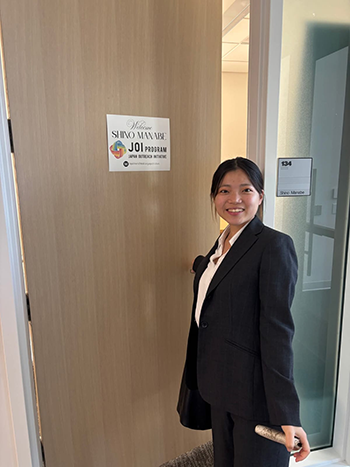 自分のオフィスのドアの前でスーツ姿の写真