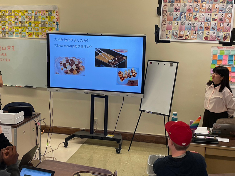 スライドを用いて日本語について教えている宮本菜摘さん。