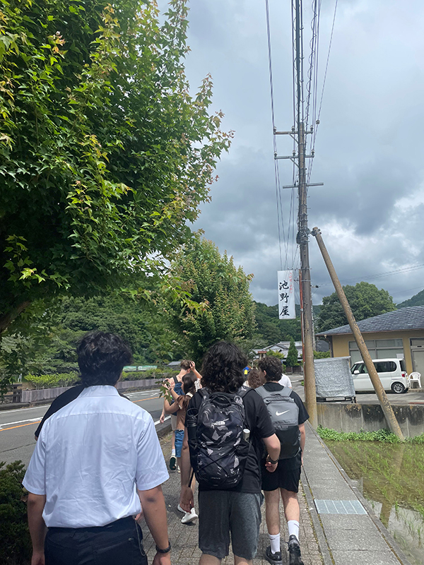 夏休みに行われたスクールトリップにて、静岡県藤枝市の道を歩く複数人の生徒たちの後ろ姿。