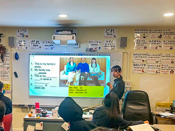 日本語の学習が行われている教室の様子。ホワイトボードやプロジェクターに例文が提示され、生徒が授業を受けている。