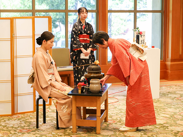 着物を着た女性たちがテーブルを使った立礼式の日本の伝統的な茶道を行っている。