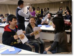 日本人ゲストに郷土料理を説明する高校生とそれを観察する先生方の写真
