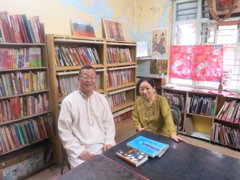 たくさんの日本語関係の書籍が置かれたテンドゥルカル美智子先生のご自宅で、先生と執筆者二人の写真。