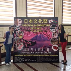 文化祭イベントの立て看板の両脇に2人の学生が立っている画像