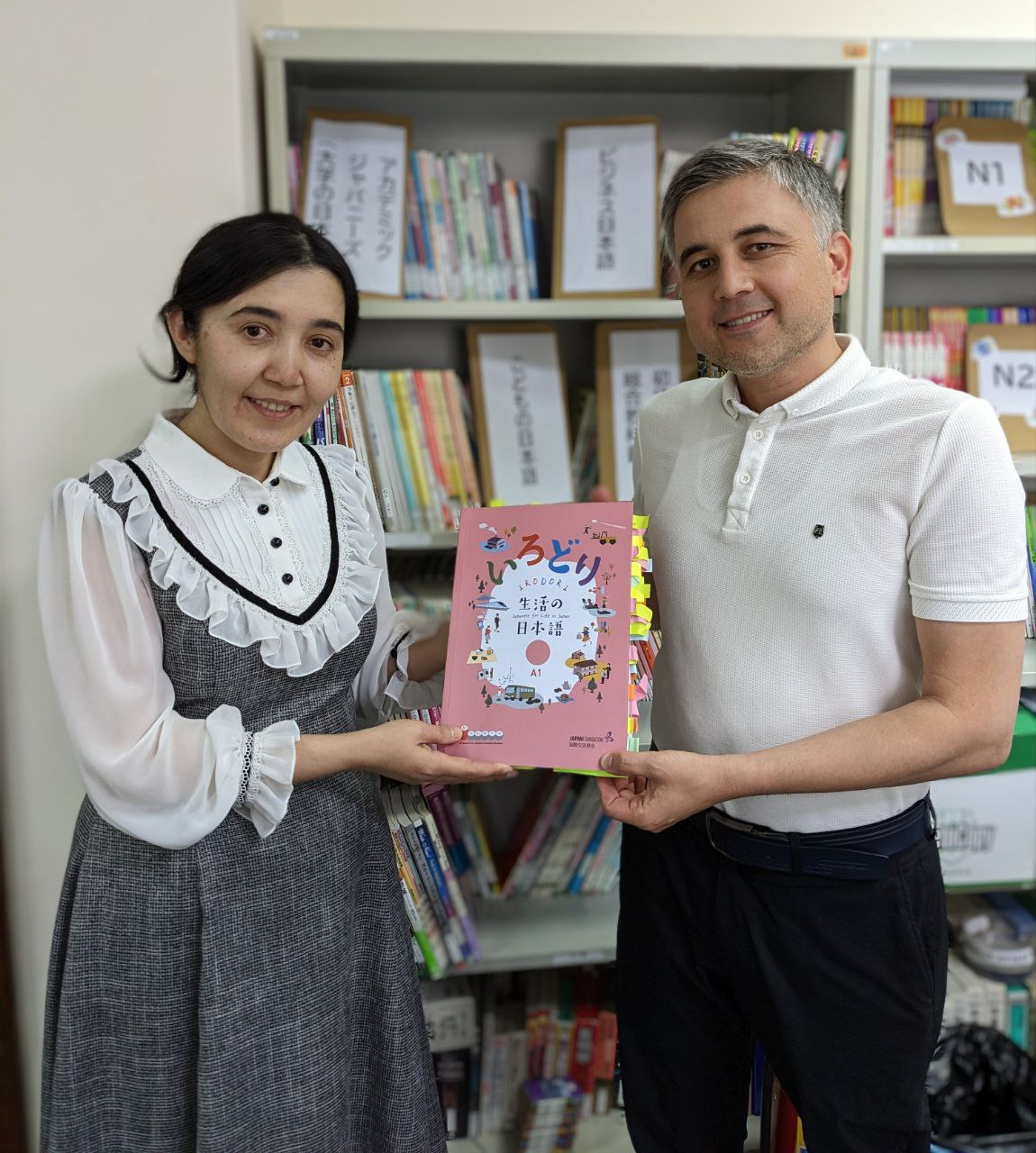 付箋がたくさんついた教科書を持った、先生の写真