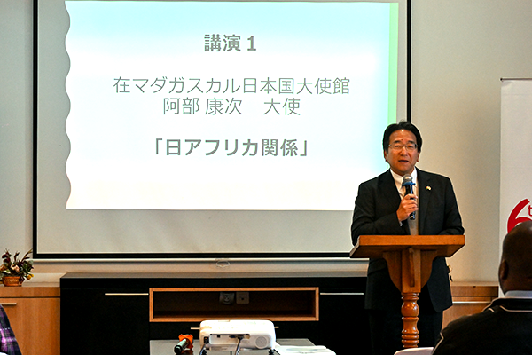 マイクを手に放すスーツの男性