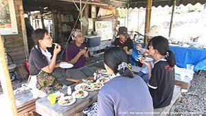屋外で料理を囲んで地域の人たちと会話しているシーンの画像