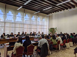 ヴェネツィアのカフォスカリ大学で開催されたヨーロッパ日本語教師会サミットの様子の写真。ラウンド型に配置されたテーブルに参加者が向かい合って座っている。