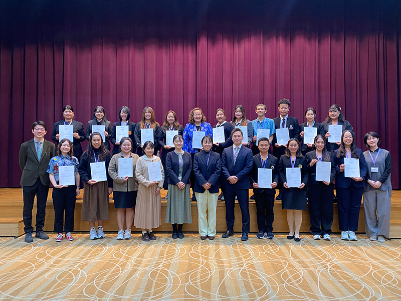 修了式の会場のステージ前で26名が並んでいる集合写真。